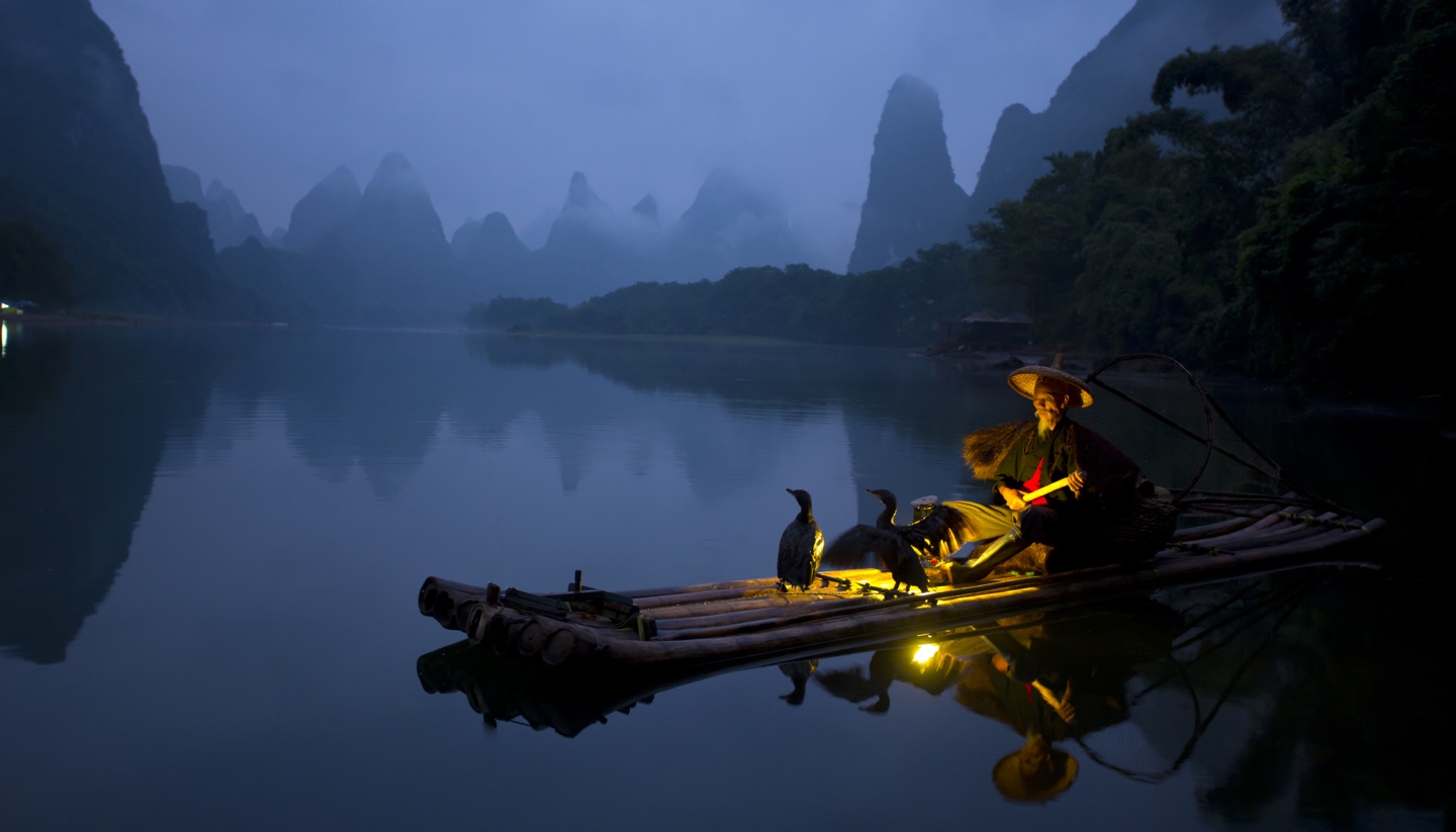 China - Fisherman and osprey in Guilin China.